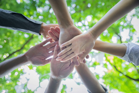 Worm's eye view of People putting their hands together. Stack of hands. Unity and teamwork concept. Team putting their hands together in circle.の写真素材