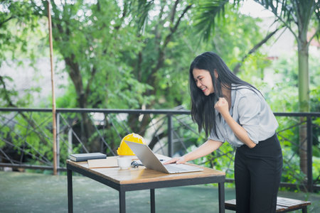 Asian female architects clenched her fist and shouted YEAH!! Glad to know that the client likes her work and agrees to sign a contract. Successful project.の写真素材