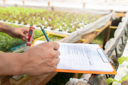 Smart agriculture technology concept - Farmer taking note water ph value of organic hydroponic plant nursery farm. Smart agriculture technology.の写真素材