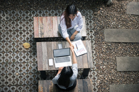 Top view of two businesswomen shaking hands over a desk.の写真素材
