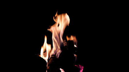 The hot embers of burning wood log fire isolated on black. Firewood burning on stove.の写真素材