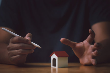 Man pointing at a model of a house with a pen. A man using white pen pointing to house model. Business, real estate and technology concept.の写真素材