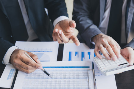 Close-up of two businessmen with pens pointing on report paper. Two Businessman discussing together...