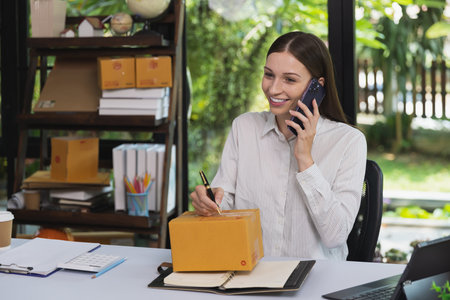 Woman are receiving orders via cell phone. Business woman owner holding parcel box for delivery...