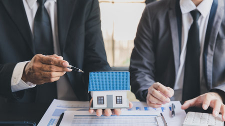 Real estate agent home sales broker is using a pen pointing to the house model and explains the business contract, rent, buy, mortgage, loan, or home insurance.の写真素材