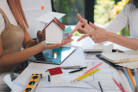 Female Architects team point to house model. Two women architects making architectural model in office together. Team of engineer meeting and discussing for house building project.の写真素材