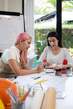 Confident team of female architect working together in a office. They discussing about new startup project on desk. Architect discuss with engineer about project in office, architectural concept.の写真素材