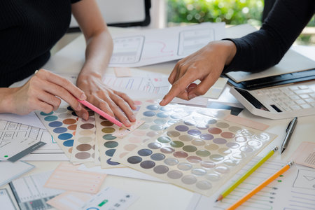 Women point to a color chart for home design. Graphic designers working on color chart at modern office.の写真素材
