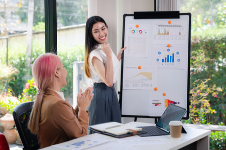 Businesswoman standing and showing joy after finishing presentation while colleagues clapping hands together admire compliment in meeting room.の写真素材