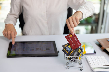 Shopping or buying with credit card concept. Woman shopping online with digital tablet. Woman holding a credit card to pay for online shopping services, invoices, utility bills and shopping cart.の写真素材