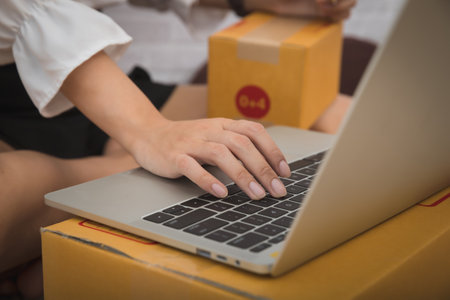 Successful entrepreneur business woman checking order via laptop with online sales and parcel shipment in her home office.の写真素材
