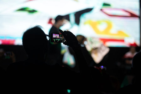 Some cheering fans using smartphone to take a photograph or video to share the moment with friends on social networks in a free live concert in music festival.の写真素材