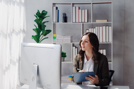 Business woman entrepreneur holding chart working with computer at office desk. Portrait of beautiful young businesswoman working at modern work station.の写真素材