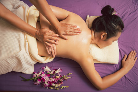 Asian woman enjoying back massage with essential oil in massage spa salon. Young girl in spa massage. Healthy treatment concept. Top view shot.の写真素材