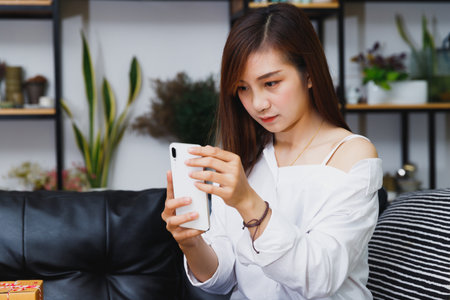 Woman  using smartphone device at home. Blogger subscribing new social media, buying in internet, ordering products online in apps.の写真素材