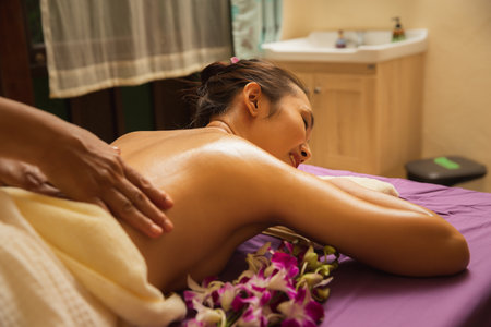 Asian woman enjoying back massage with essential oil in massage spa salon. Young girl in spa massage. Healthy treatment concept.の写真素材