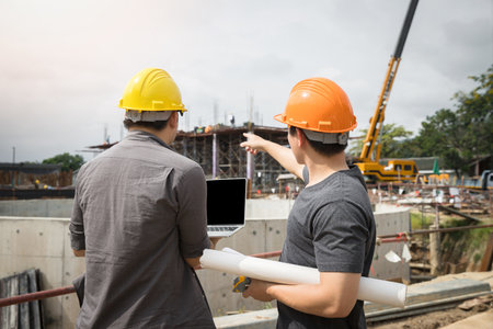 Team of construction workers discussing project details with blueprint in construction site.の写真素材