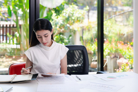 Young businesswoman working with documents in office. Businesswoman holding papers preparing report analyzing work results.の写真素材