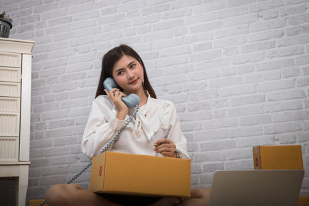 Woman receiving orders via retro telephone. Successful entrepreneur business woman with online sales and Parcel shipping in her home office.の写真素材