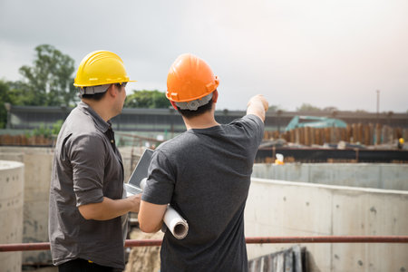 Team of construction workers discussing project details with blueprint in construction site.の写真素材
