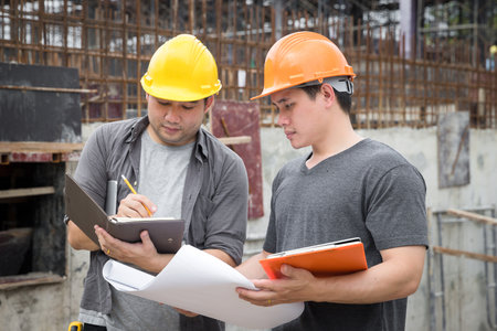 Team of construction workers discussing project details with blueprint in construction site.の写真素材