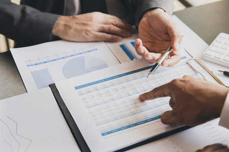 Close-up of two businessmen with pens pointing on report paper. Business team presentation meeting Asian Men Finance Executive discusses meetings to plan work, investment projects.の写真素材