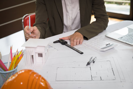 An architect woman or engineer woman working on blueprint with model house in office, architectural concept.の写真素材