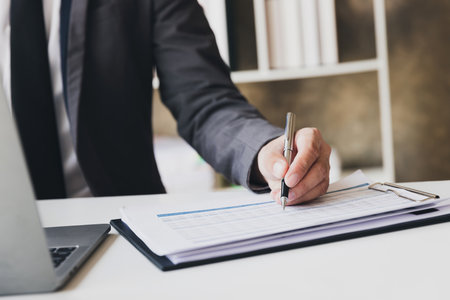 Businessman pointing monthly graph chart. Data analyzing to find out the result. Businessman writing or pointing on report paper. Business strategy concept.の写真素材