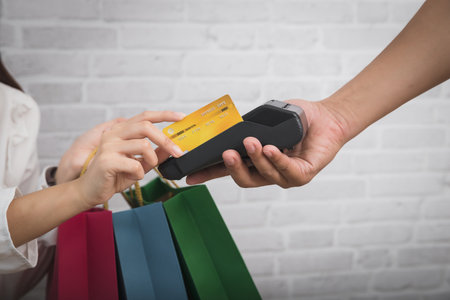 Salesman holding a credit card swipe machine or electronic data capture along with accepting credit cards from customers. Customer using credit card for payment.の写真素材