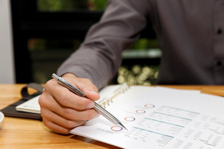 Businessman holding a pen with documents in home office.の写真素材