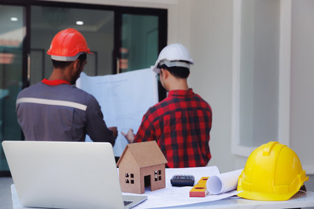 House model on desk over confident team of architects working together in a office. Architect discuss with engineer about project in office, architectural concept.の写真素材