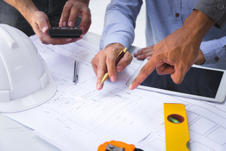 Architects point at blueprint. Architects Brainstorming idea to design consulting and analyzing on blueprint and model building in working construction site.の写真素材