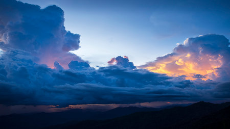 Stunning mountain landscape at sunset with dark storm clouds and golden light breaking through. Perfect for themes of nature, weather, and outdoor beauty.の写真素材