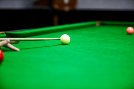 A close-up shot of a snooker player aiming at the cue ball on a green table. A game of precision, focus, and skill in action.の写真素材