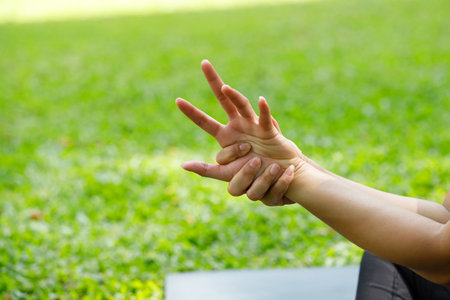 Close-up of a hand stretching exercise in the park. Gentle outdoor activity for joint flexibility,...