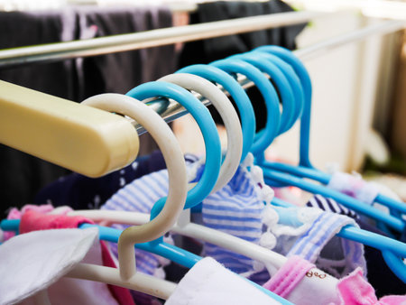 Plastic kid hangers on metal rack in homeの写真素材