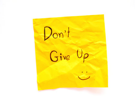 Write don't give up on yellow post note isolated on white backgroundの写真素材