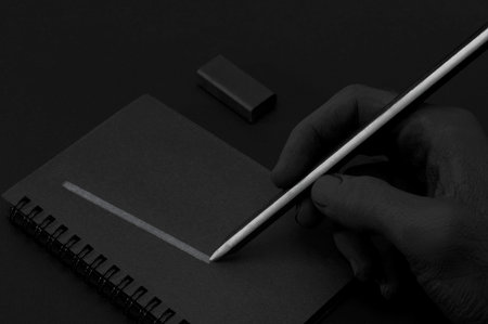 black hand writing on black notebook with black eraserの写真素材