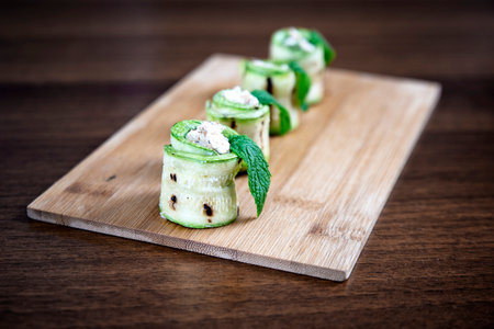 Grilled zucchini rolls with goat cheese on wooden plateの写真素材