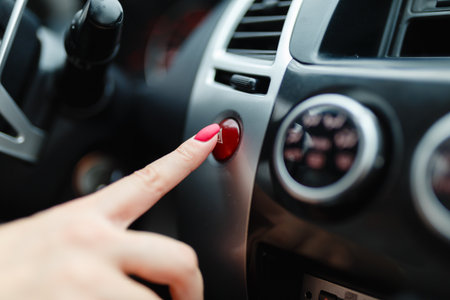 The female hand presses the button to turn the alarm into the car. Button emergency car lighting shot of a finger. Woman finger pressing emergency button on car dashboardの写真素材