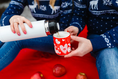 Girl pours tea in a mug with a picture of the heart.の写真素材