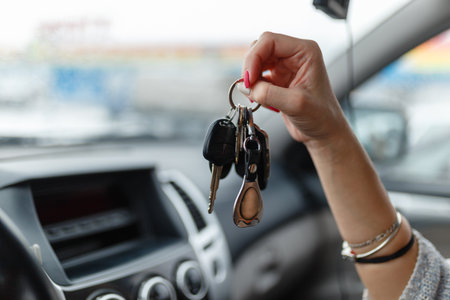 Car keys in the hand of a girl in the car interior. Woman holding car keys. Close up Handの写真素材