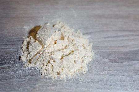 Product photograph of spoon or measuring scoop of whey protein on grey wooden background. Dry mixture for dilution with milk or water.の写真素材
