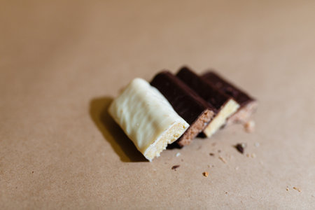 Four chocolate protein bars with different flavors in the context of sprinkle rice flakes on baking paperの写真素材