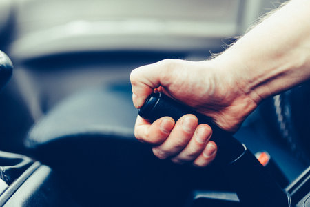 The driver pulls the hand brake lever. Male hand pulling the Parking brake using the hand brake...