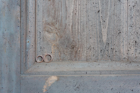 Wedding rings on a wooden door in the corner. Wedding rings hanging on rope over wooden background. Vintage image.の写真素材