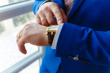 Man in a blue expensive suit and vest looks at expensive watches. closeup designer watch on businessman hand, he looks on the time and hurryingの写真素材
