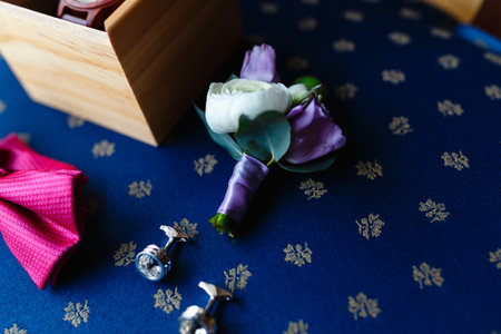 Flower boutonniere. A men's set of accessories on an old wooden chair with a soft blue seat. Set of...