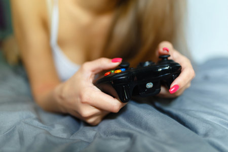 Girl gamer playing with a wireless controller, looking at the screen in front. Young girl eSports...