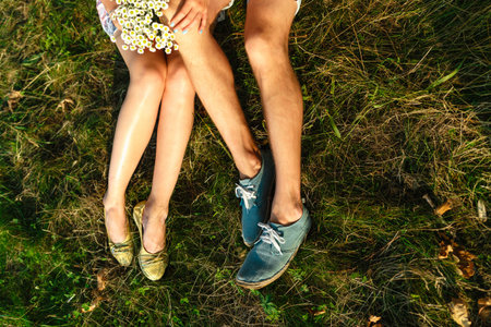 Summer top view of romantic man and woman lying on the field. The concept of a beautiful family. Young couple lying on a green meadow. A girl in summer sandals and a man in sneakers.の写真素材